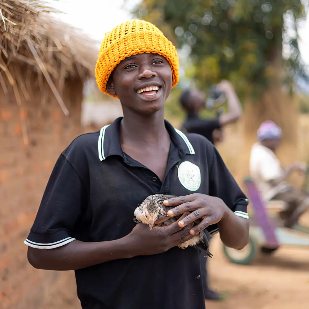Person holding a chicken outdoors.