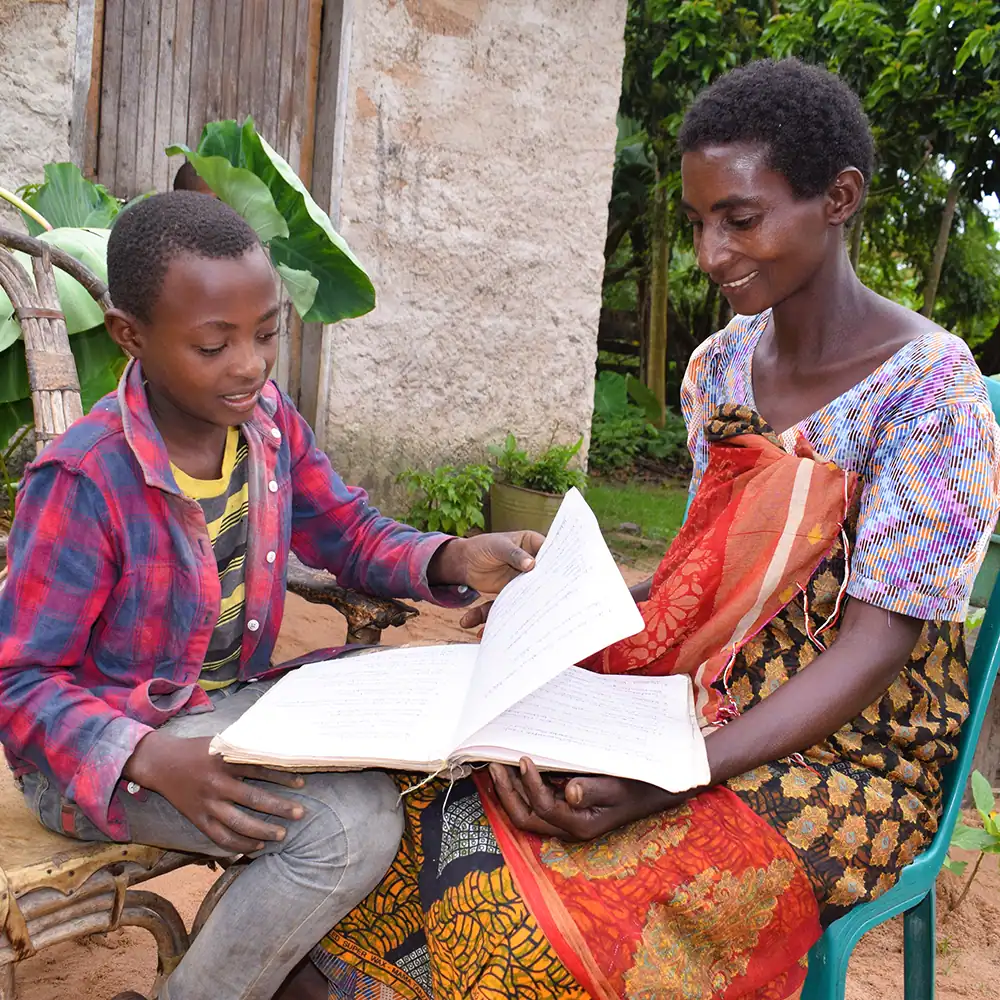 Two people reading children's books together outdoors.