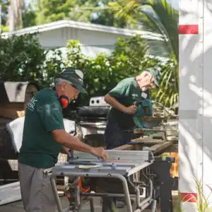 Volunteers using tools while working to clean up after a disaster on home repairs outdoors.