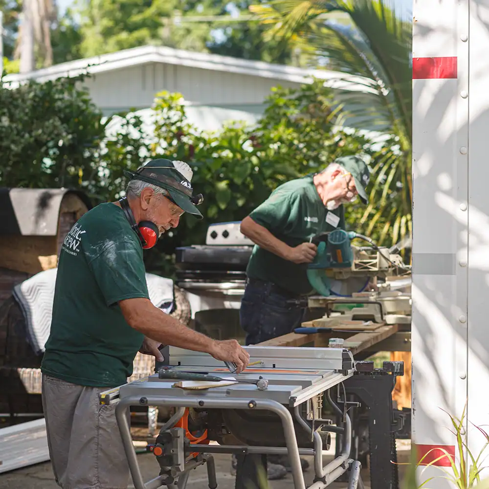 Volunteers using tools while working to clean up after a disaster on home repairs outdoors.
