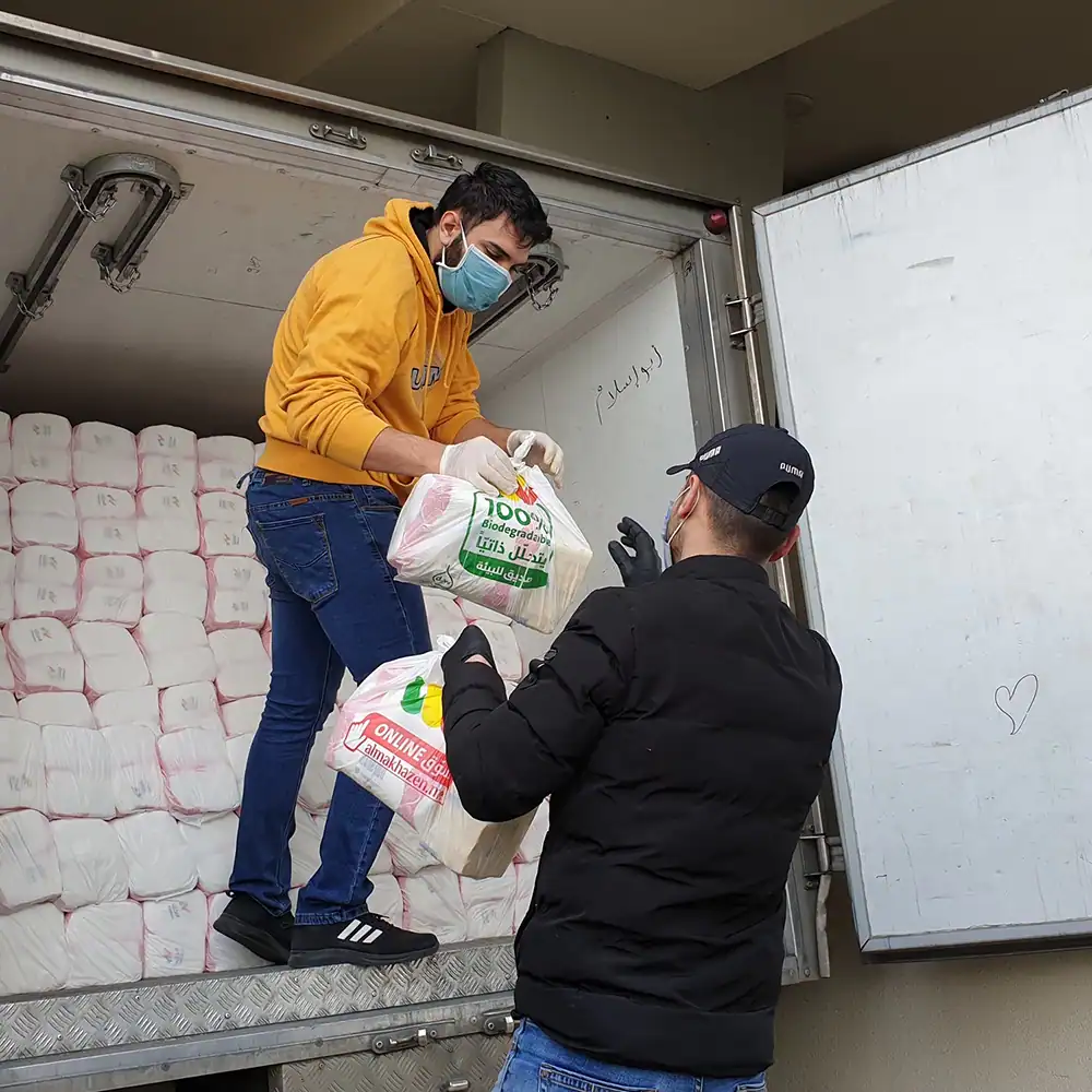 Two volunteers unloading soap, toothpaste, toothbrushes, tissues, diapers, and other emergency hygiene supplies from a box truck.