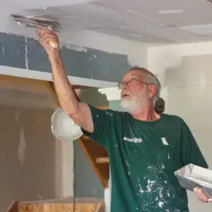Volunteer using a drywall tool during a home repair project.