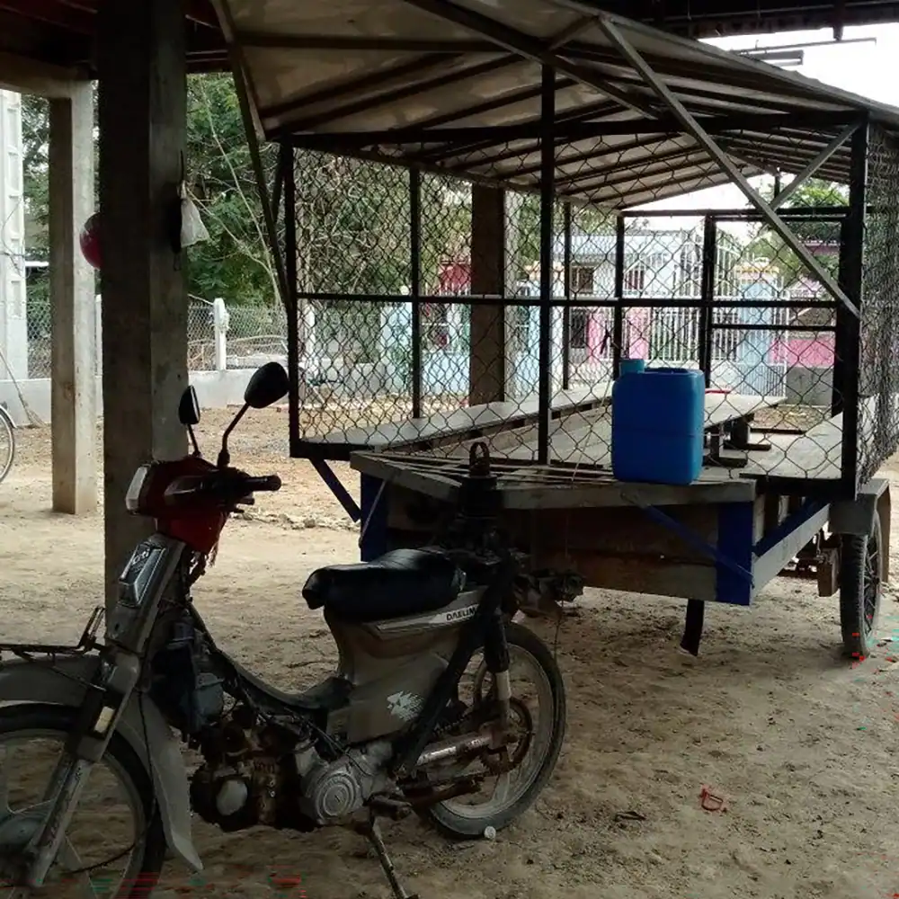 Motorbike and book trailer parked under a covered shelter.