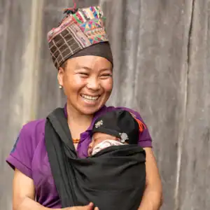 Person carrying a young child in a front wrap.