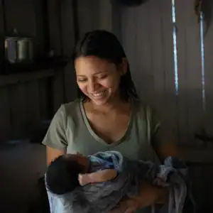 Caregiver holding and feeding a baby indoors.