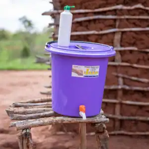 Handwashing station with a water container and tap set outdoors.