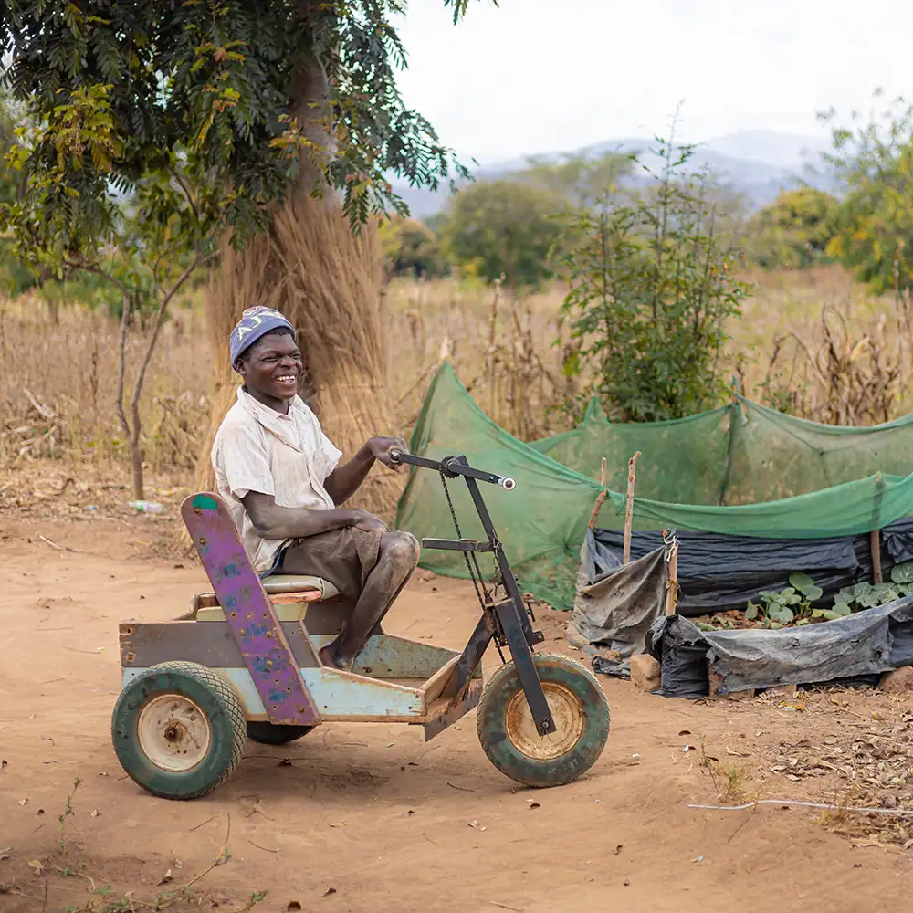 Person using a wheelchair outdoors on a dirt path.